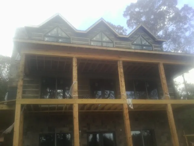 Dormers and porch framing on a large log home under construction — Roof Coating work by our crew in Mount Enterprise