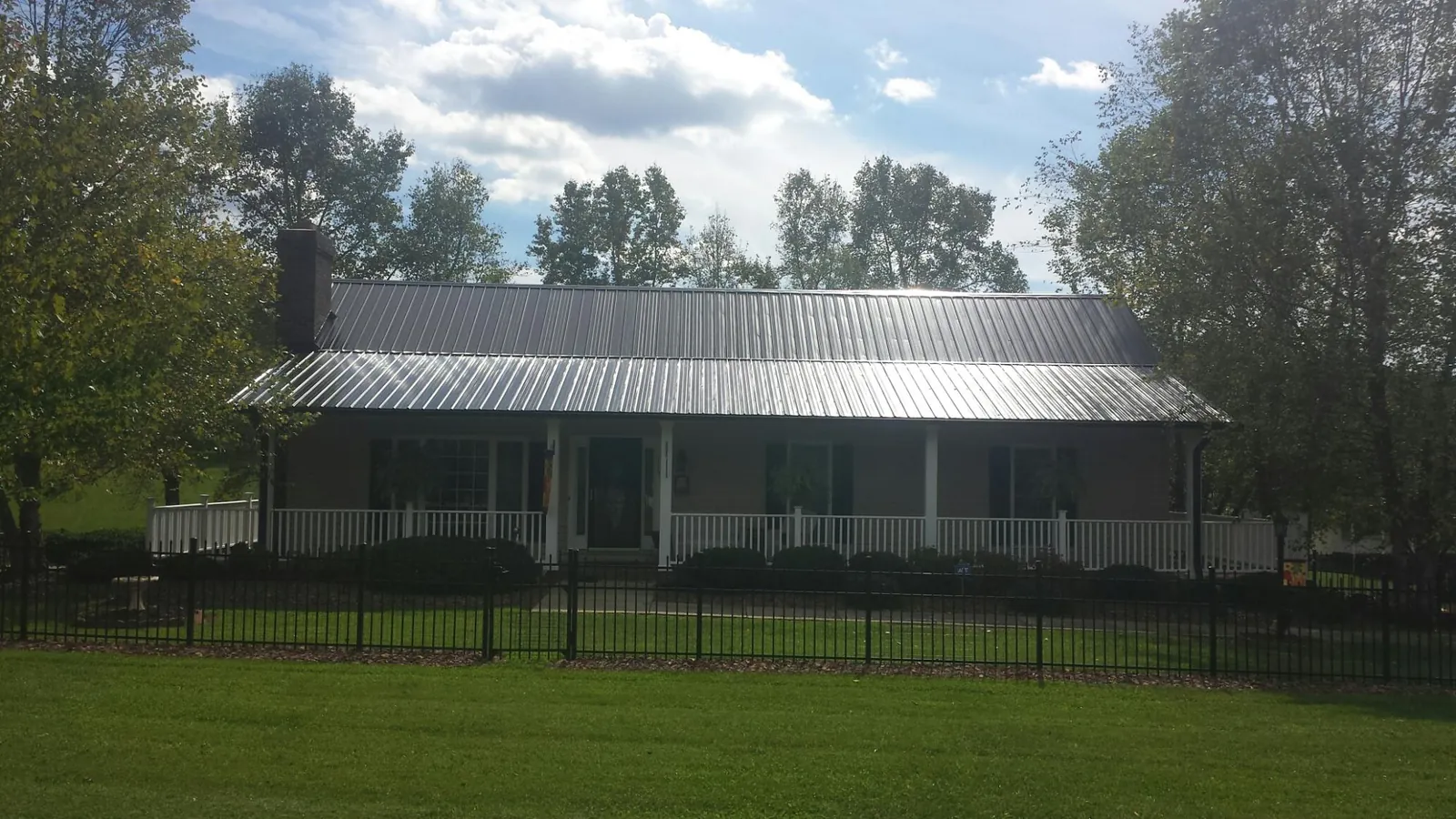 Gray metal roof on a brick ranch with a full width front porch — Gutter Guard Installation work by our crew in Mount Enterprise