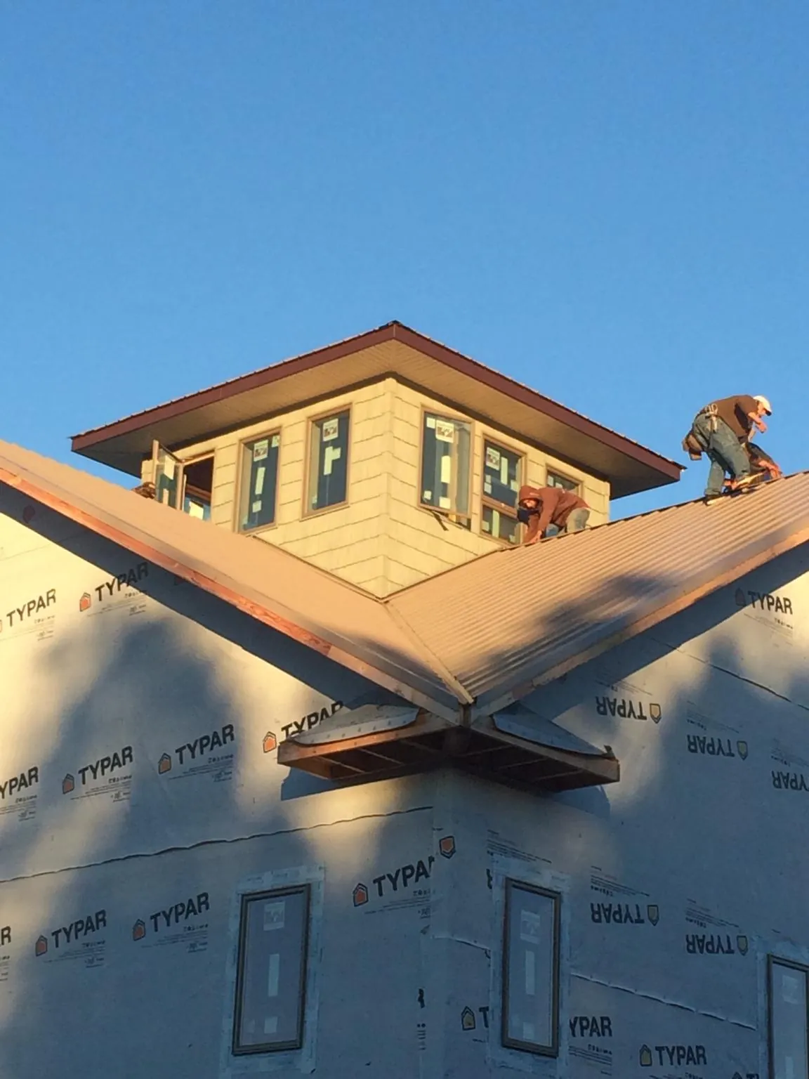 Roofers working around a rooftop cupola on a new metal roof at sunset — Roof Waterproofing in Mount Enterprise by Roofing Brothers